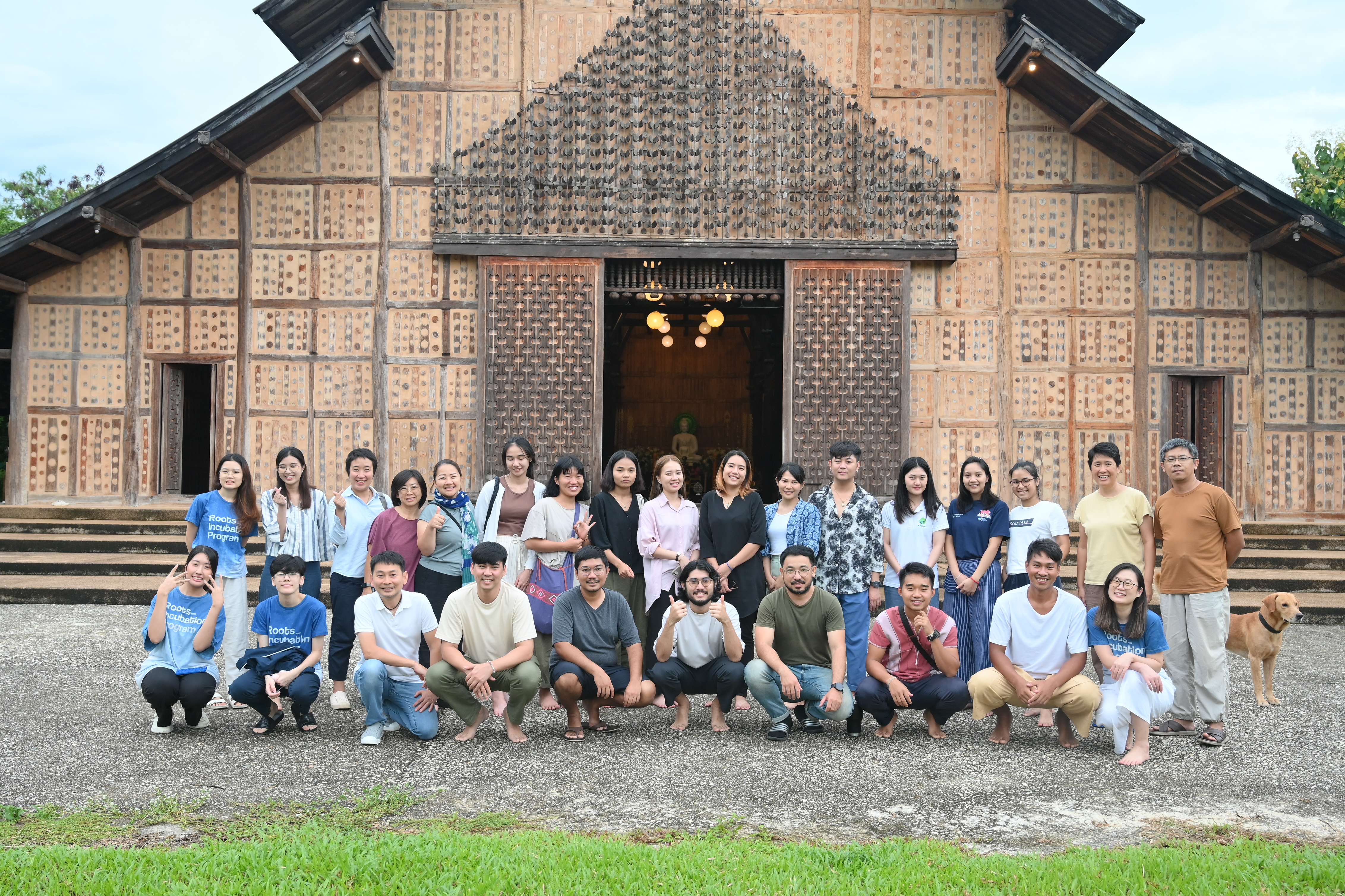 A group of people posing in front of a tall traditional house