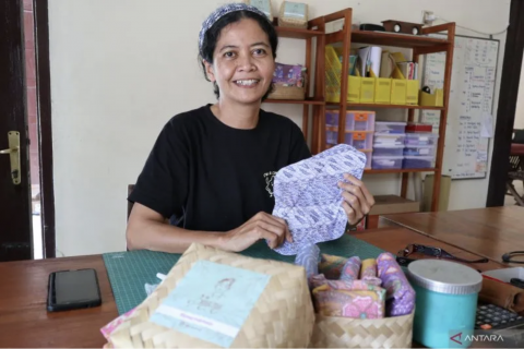 A smiling woman at a desk shows cloth diapers. 