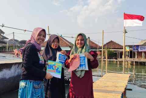 Three Indonesian hijabis hold up informational booklets