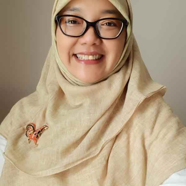 Photo of Adinindyah Arya Wisnutama (Indonesian woman wearing glasses, a cream hijab, and a rooster brooch)