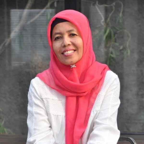 Photo of Masnu’ah (seated Indonesian woman wearing a pink hijab and white shirt)