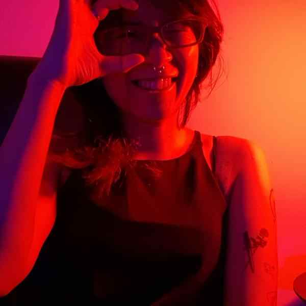 Photo of Wipaphan Wongsawang (Thai woman in red lighting forming a "C" with two fingers around one of the lenses of her glasses)