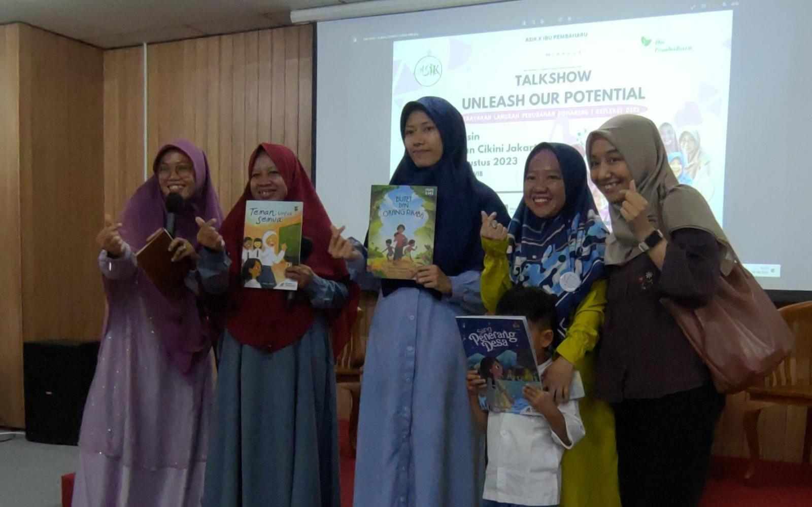 A group of Indonesian women hold up illustrated children's books