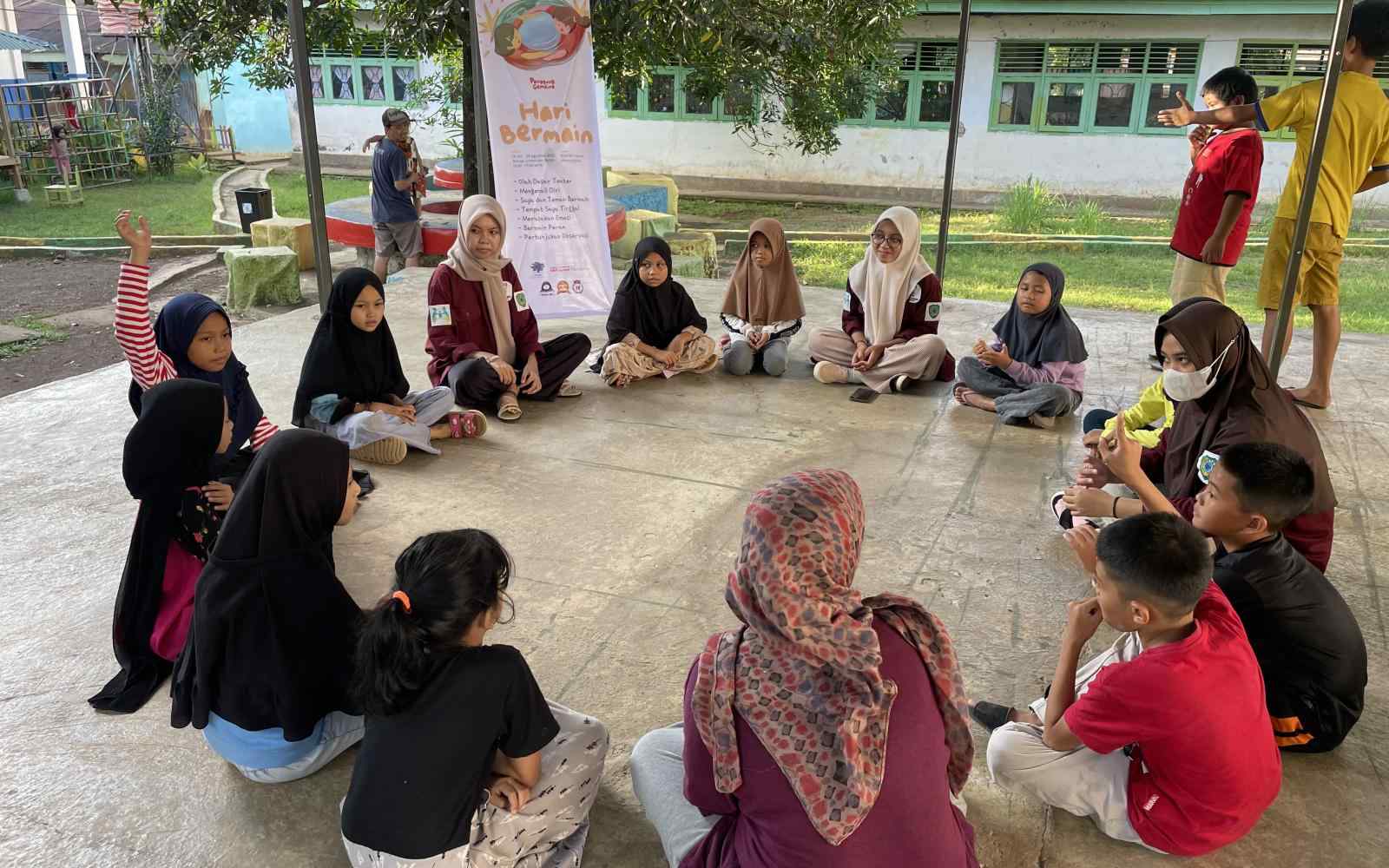 A circle of Indonesian women and children sitting on the ground