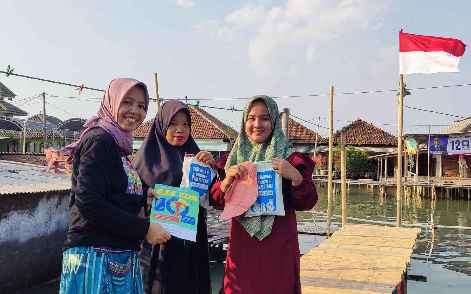 Three Indonesian hijabis hold up informational booklets