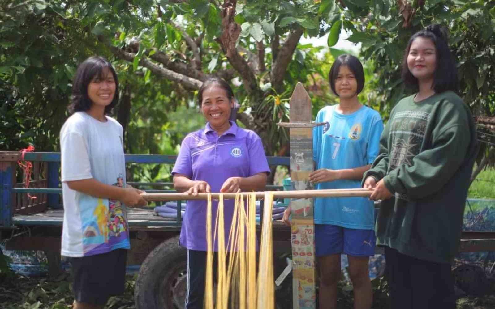 Four Indonesian women stand in front of a loom