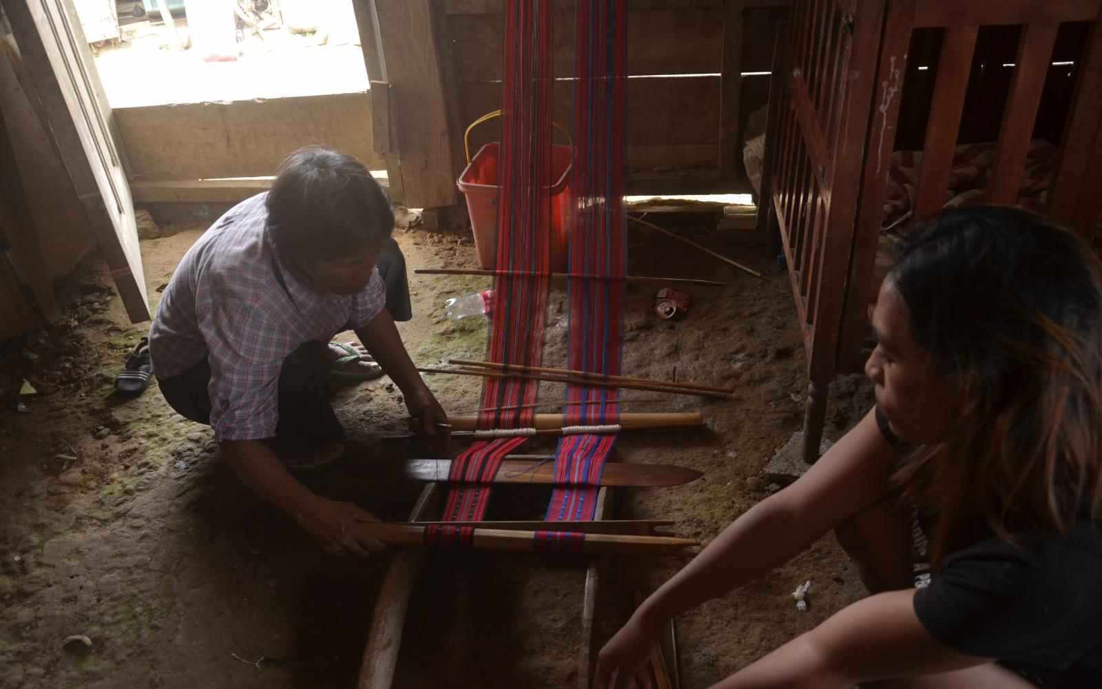 Two Filipinas using a loom