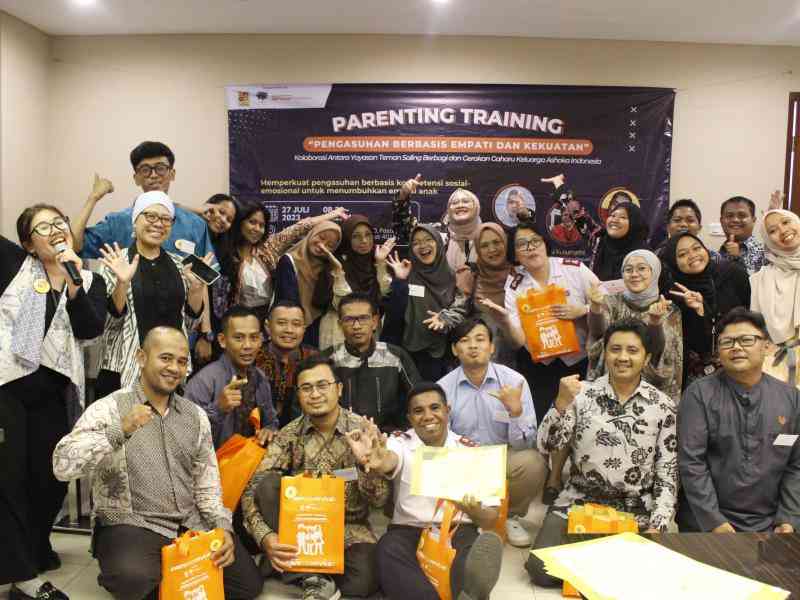 A group of people pose in front of a sign that says "Parenting Training"