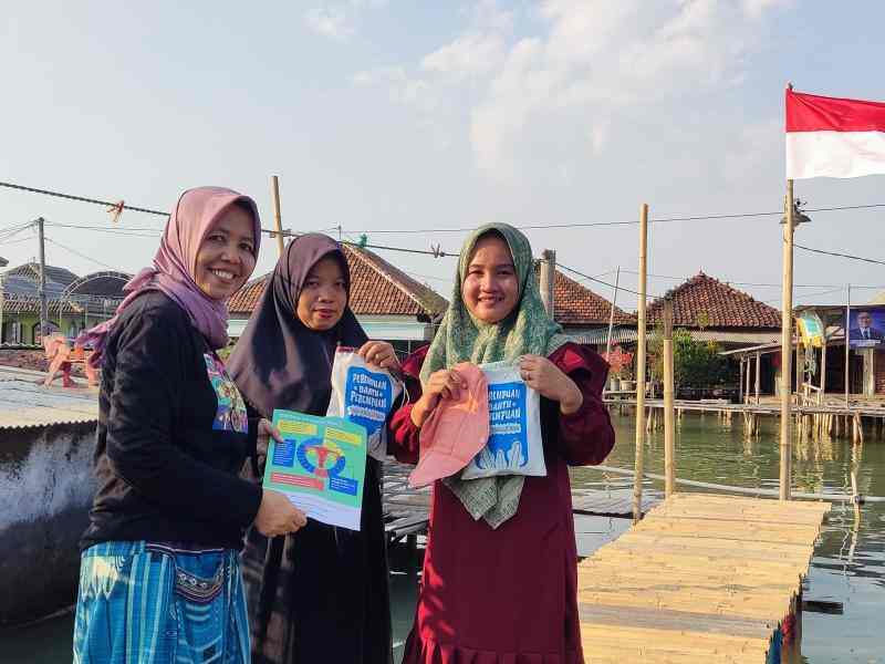 Three Indonesian hijabis hold up informational booklets