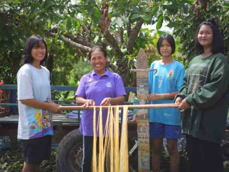 Four Indonesian women stand in front of a loom