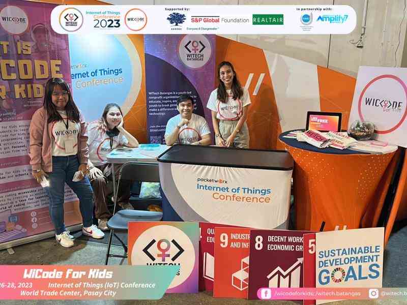 A group of people smile and are positioned at an event booth